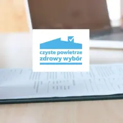 Dłoń pisząca na formularzu, logo "czyste powietrze zdrowy wybór".